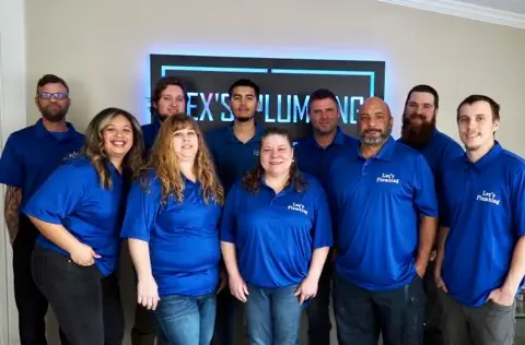 Lex's Plumbing team in branded uniforms in front of company sign